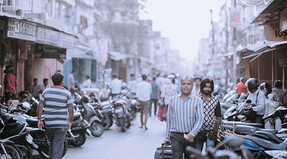 history slider imgae Eine mit Motorrädern und Menschen gefüllte Seitenstrasse in Indien.